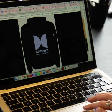 Hand werkt op laptop met ontwerpsoftware voor marketing, gericht op het creëren van campagnes en evenementen