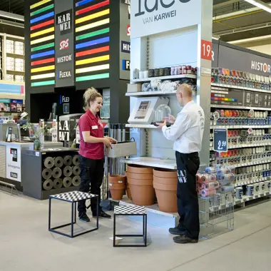 Medewerker helpt klant bij het kiezen van producten in een winkelomgeving met verf en klusartikelen