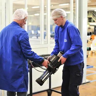 Technici in een productieruimte werken samen aan het installeren en controleren van machinedelen.