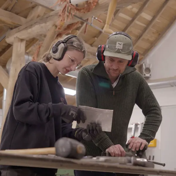 Twee studenten werken samen aan een ontwerp in een werkplaats, gefocust op ruimtelijk vormgeven.
