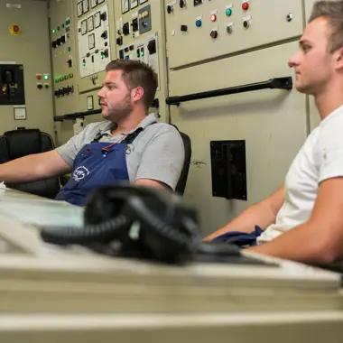 Maritiem student bedient apparatuur in de stuurhut tijdens een praktijkles navigatie en techniek.
