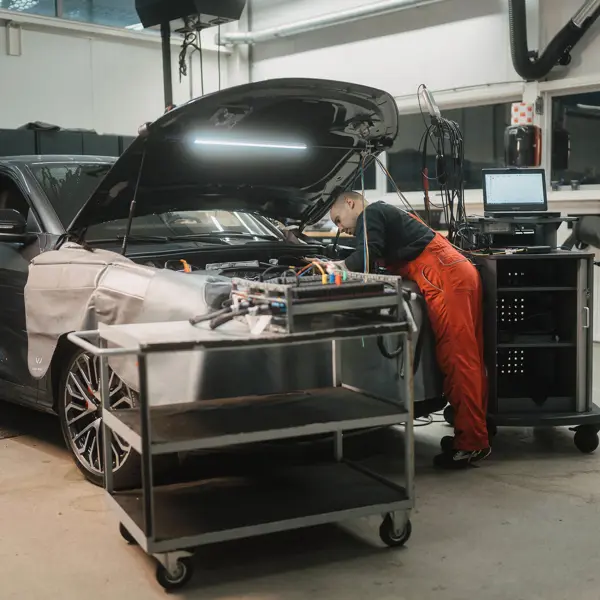 Technisch specialist onderzoekt en repareert complex voertuig in werkplaats met diagnoseapparatuur.