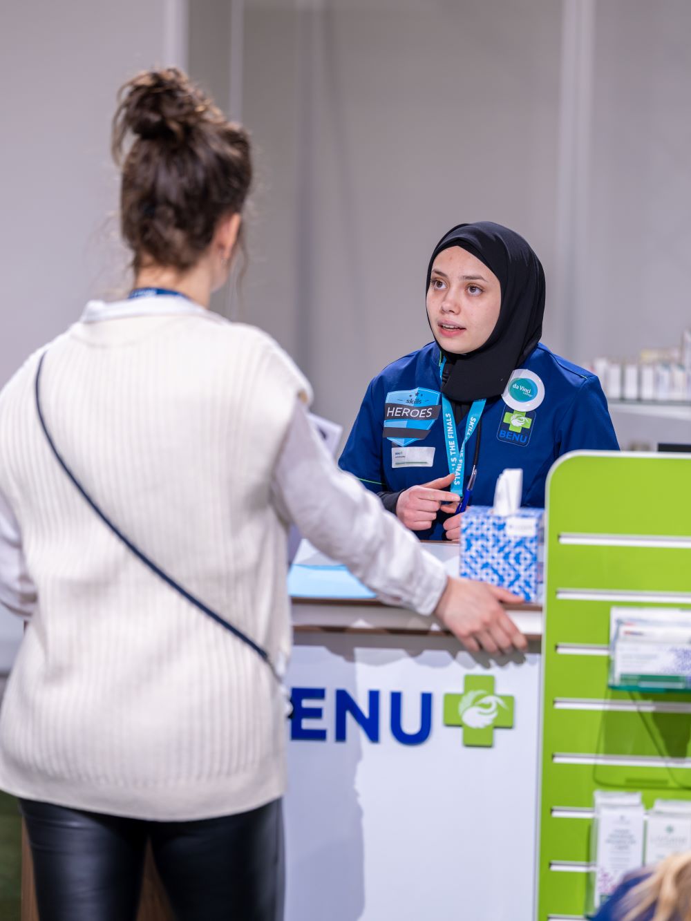 Apothekersassistent geeft advies aan een bezoeker over het gebruik van medicijnen achter de balie