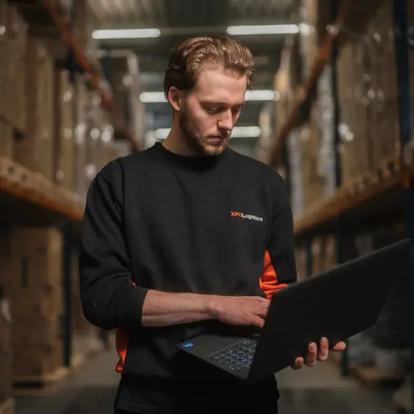 Medewerker controleert voorraadgegevens op laptop in een magazijnomgeving.
