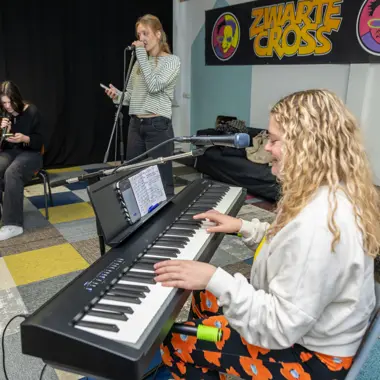 Studenten oefenen samen met zang, toetsinstrument en gitaar tijdens een muziek en entertainment sessie