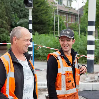 Twee medewerkers in veiligheidshesjes overleggen bij een bouwlocatie gericht op infrastructuur werkzaamheden.