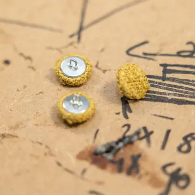 Kleine knopen gebruikt voor stoffering liggen op een patroonpapier met tekeningen en maten