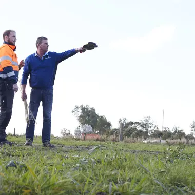 Drie vakmensen overleggen buiten over plannen voor werkzaamheden in de groene ruimte