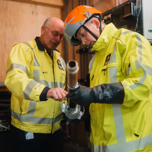 Elektrotechnicus en begeleider werken samen aan assemblage van technische installatie in professionele omgeving