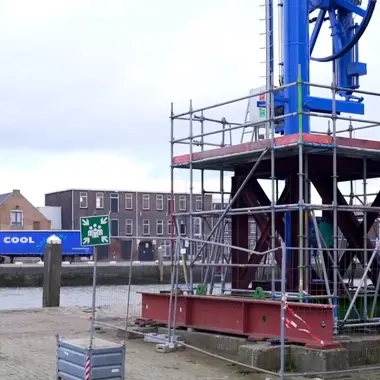 Technici controleren en monteren een metalen constructie op een kade in een industriële omgeving