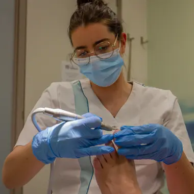 Medisch pedicure verzorgt een cliënt en gebruikt professionele apparatuur voor voetbehandeling.
