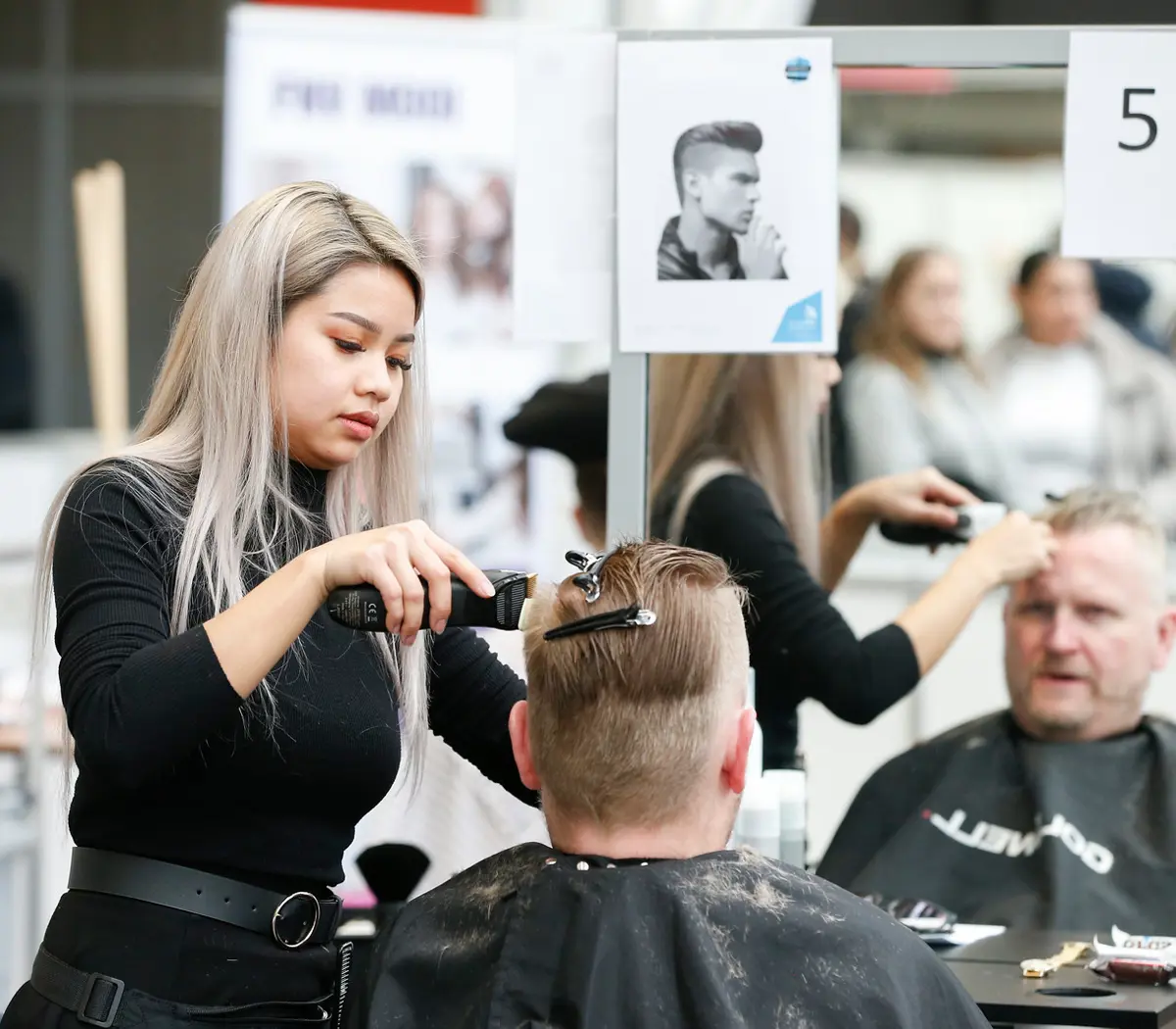 Barbiersstudent oefent knippen en stylen van haar in een salonsituatie met spiegel en klant.