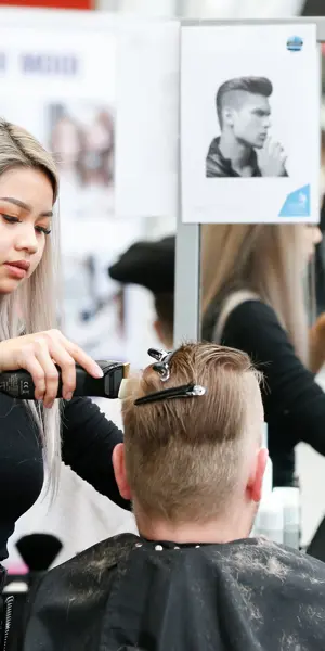 Barbiersstudent oefent knippen en stylen van haar in een salonsituatie met spiegel en klant.