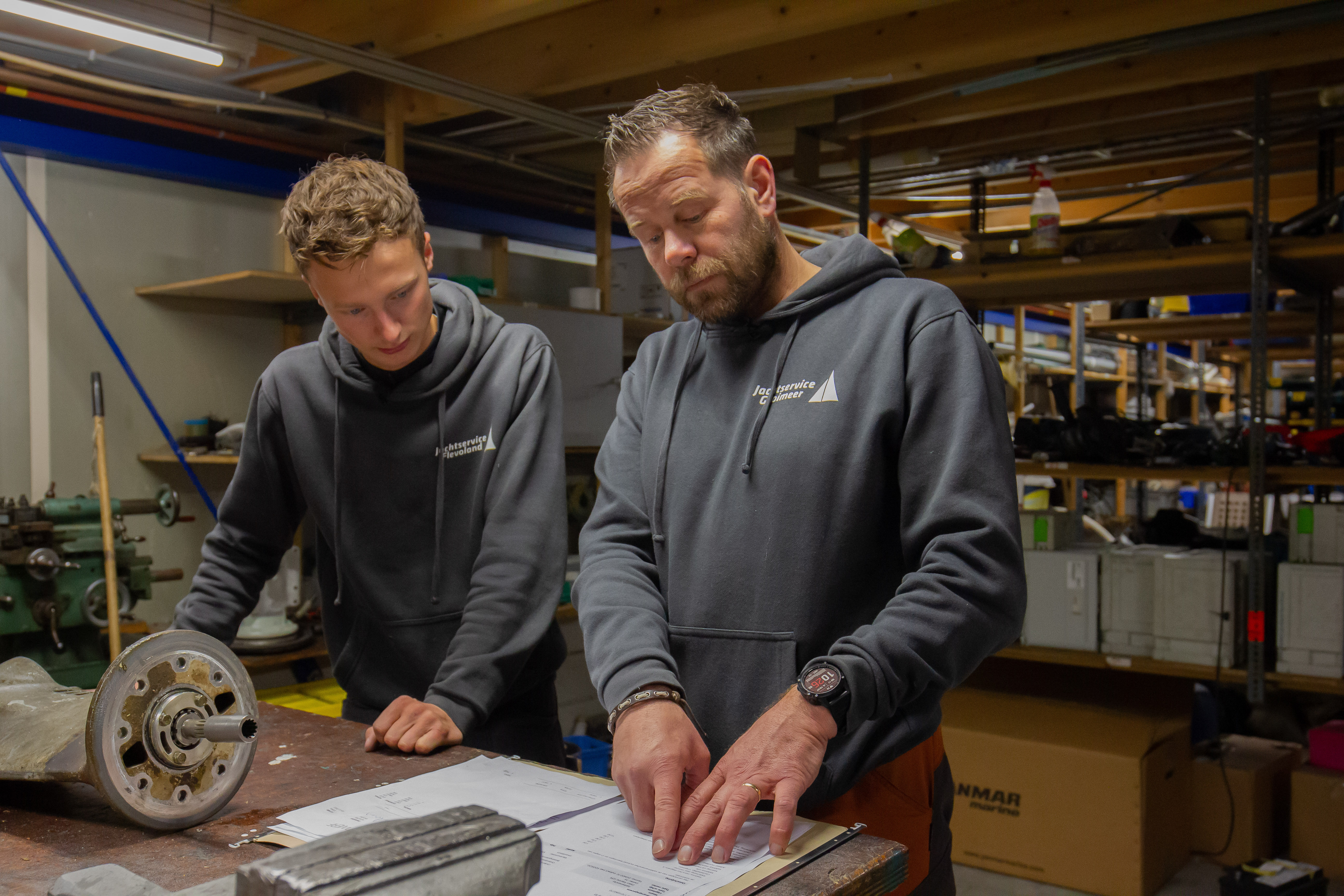 Medewerkers maritieme techniek bestuderen technische tekeningen in een werkplaatsomgeving