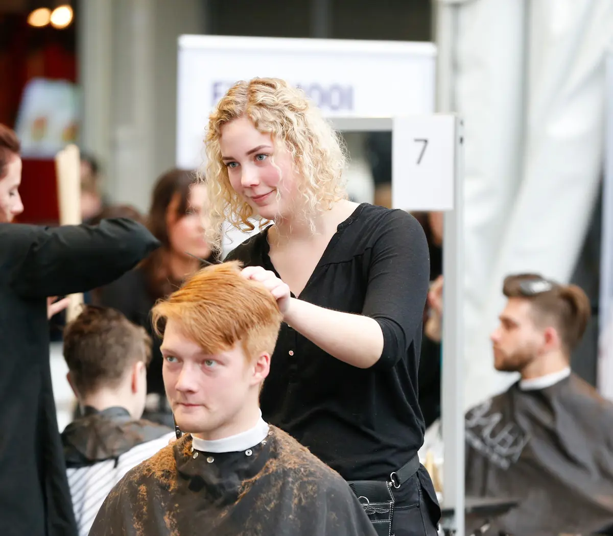 Leerling knipt en stylet een herenkapsel tijdens praktijkles uiterlijke verzorging in een kappersstudio