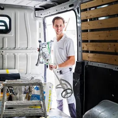 Vakman bereidt gereedschap voor om materiaal aan te brengen bij werkzaamheden in een bestelwagen