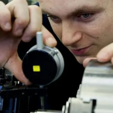 Leerling bekijkt en stelt nauwkeurig een meetinstrument af tijdens een techniekles met metaalbewerking.