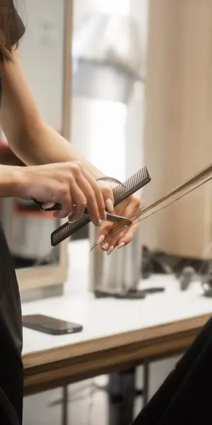 Een kapper oefent kniptechnieken op haar klant in een trainingsomgeving.