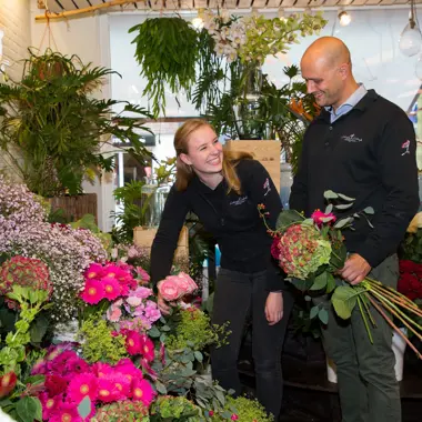 Twee vakbekwame medewerkers groen werken samen aan bloem- en plantstyling in een bloemenwinkel