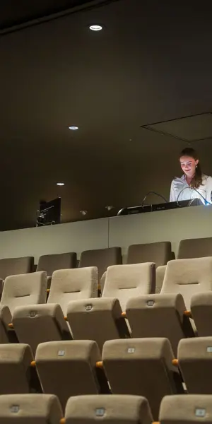 Technicus bedient apparatuur in een zaal tijdens de organisatie van een evenement.
