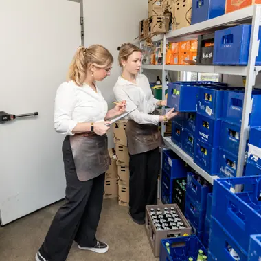 Medewerkers controleren en sorteren drankvoorraden in een magazijn voor horeca en recreatie