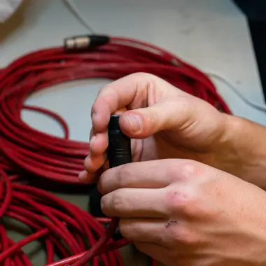Technicus die kabelverbinding maakt bij podiumapparatuur voor licht en geluid
