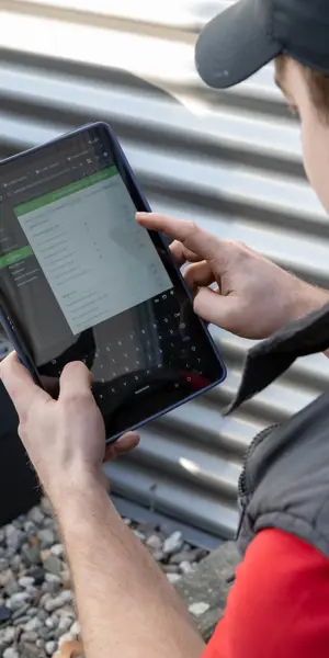 Monteur controleert technische gegevens op een tablet bij een Toshiba airco-installatie buiten.