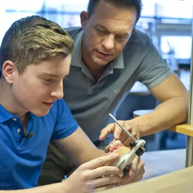 Student en docent werken samen aan een medisch technisch apparaat in een leeromgeving