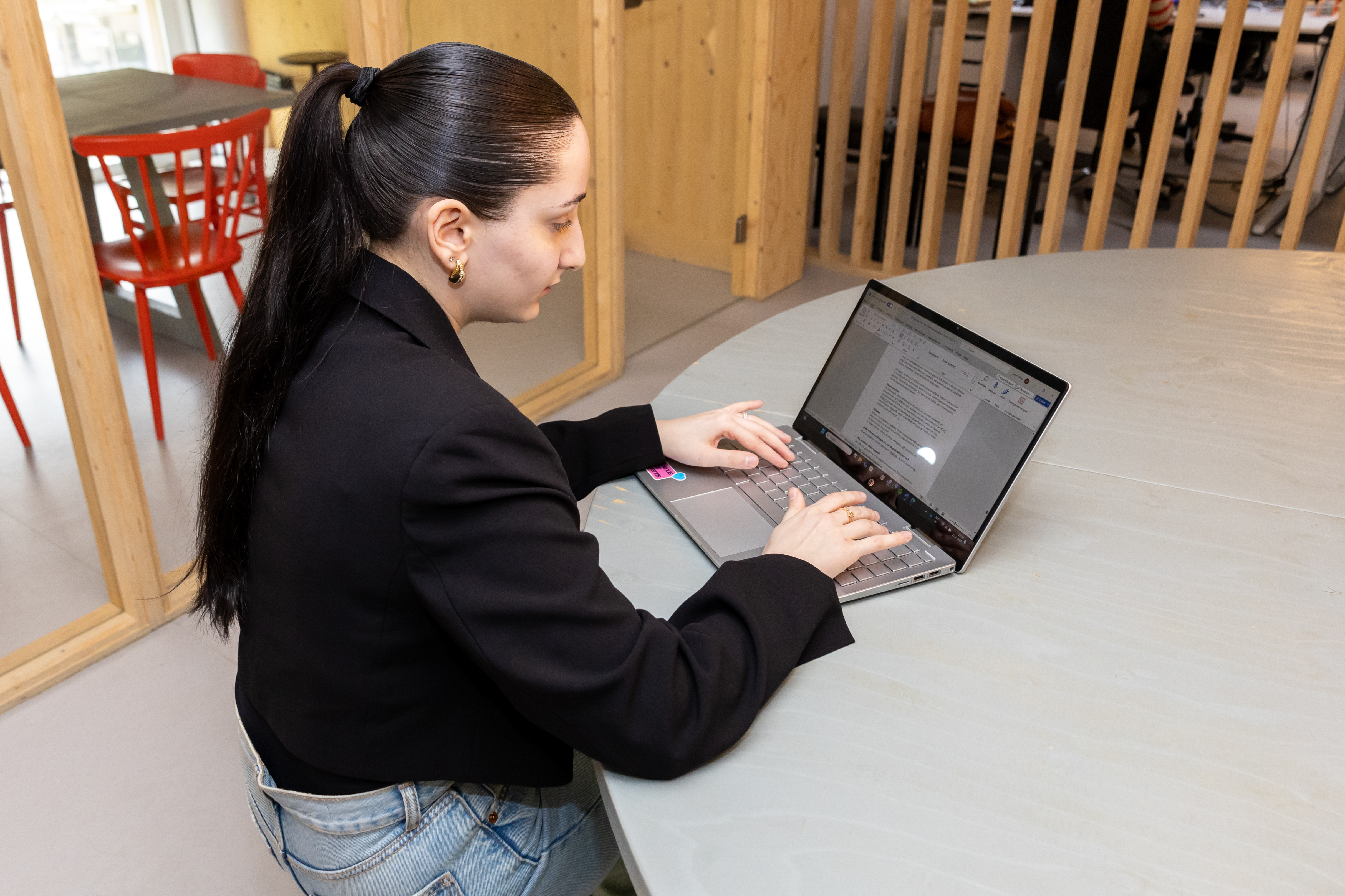 Student werkt geconcentreerd op een laptop aan een ontwerp gerelateerd aan communicatie en media