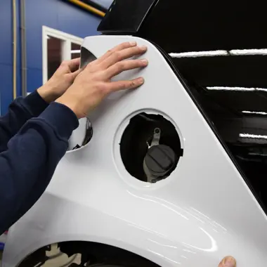 Technicus plaatst een auto carrosseriedeel, gericht op herstel en vormgeven van voertuigen.