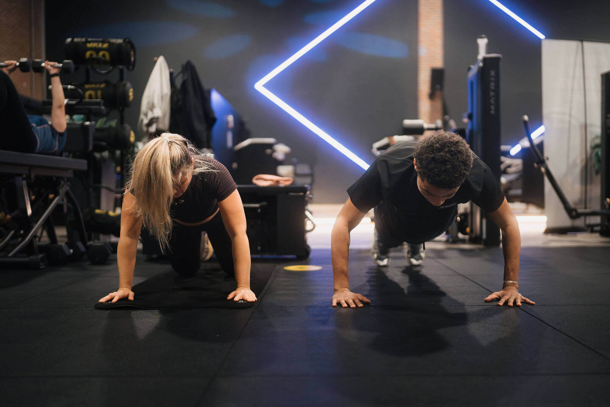 Twee mbo-studenten doen samen krachttraining in een sportschool.