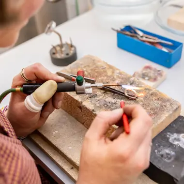 Student werkt geconcentreerd aan het maken van sieraden met een brander en fijn gereedschap