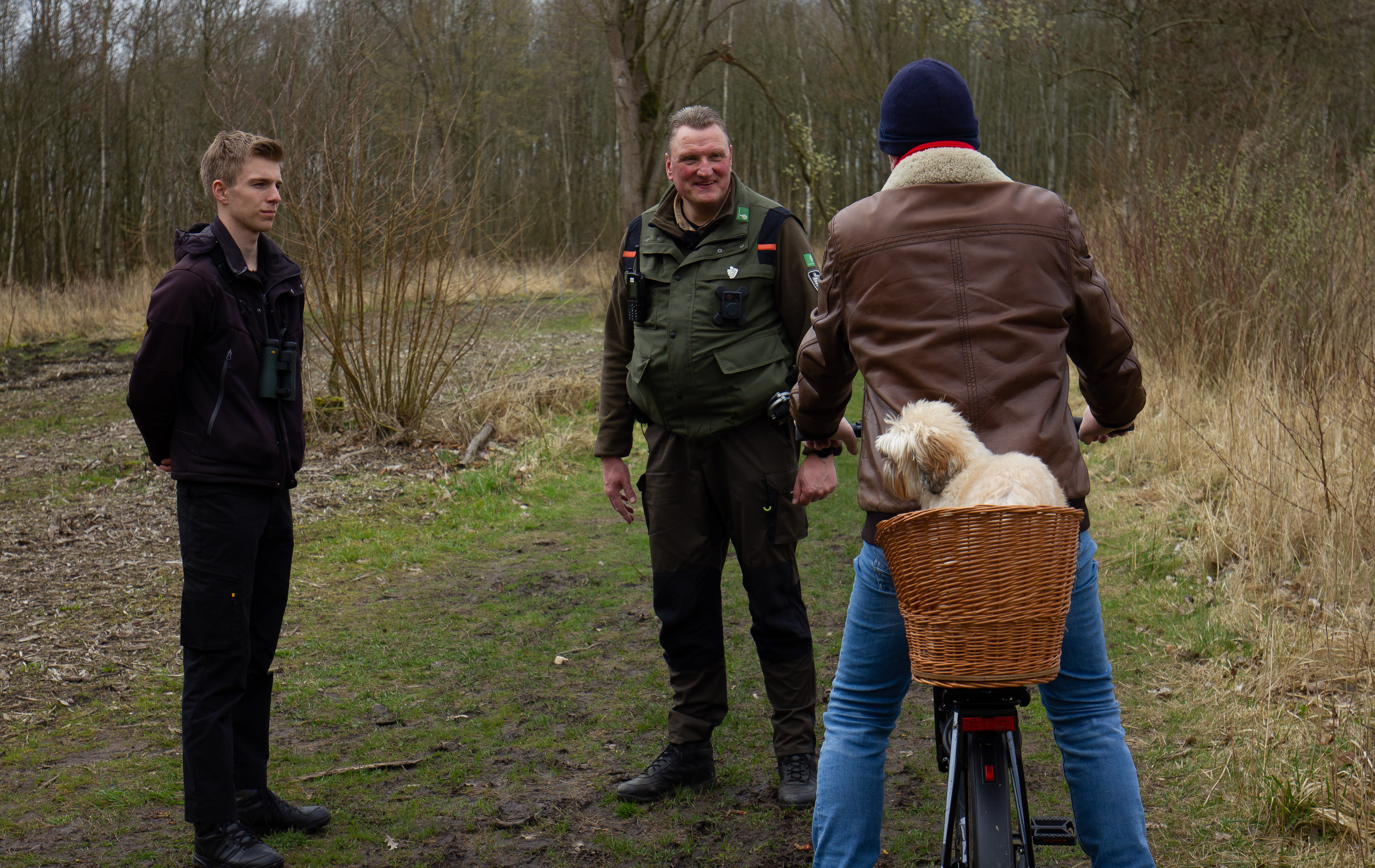 Handhavers in gesprek in een bosrijke omgeving tijdens toezicht op natuur en milieu.