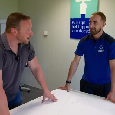 Twee medewerkers bespreken technische details tijdens een overleg in een bedrijf voor watervoorziening.