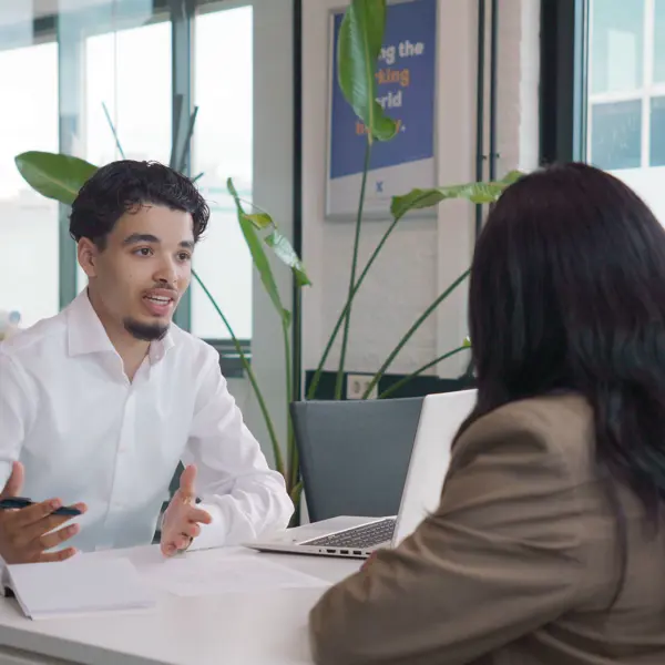 Een consulent commerciële arbeidsbemiddeling bespreekt een opdracht met een cliënt op een kantoor.