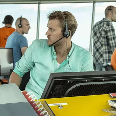 Medewerker bedient apparatuur en communiceert tijdens coördinatie van maritiem transport op de brug.