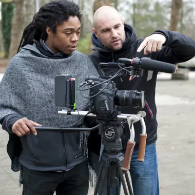 Twee medewerkers werken samen aan de opname van een project met professionele videocamera op statief