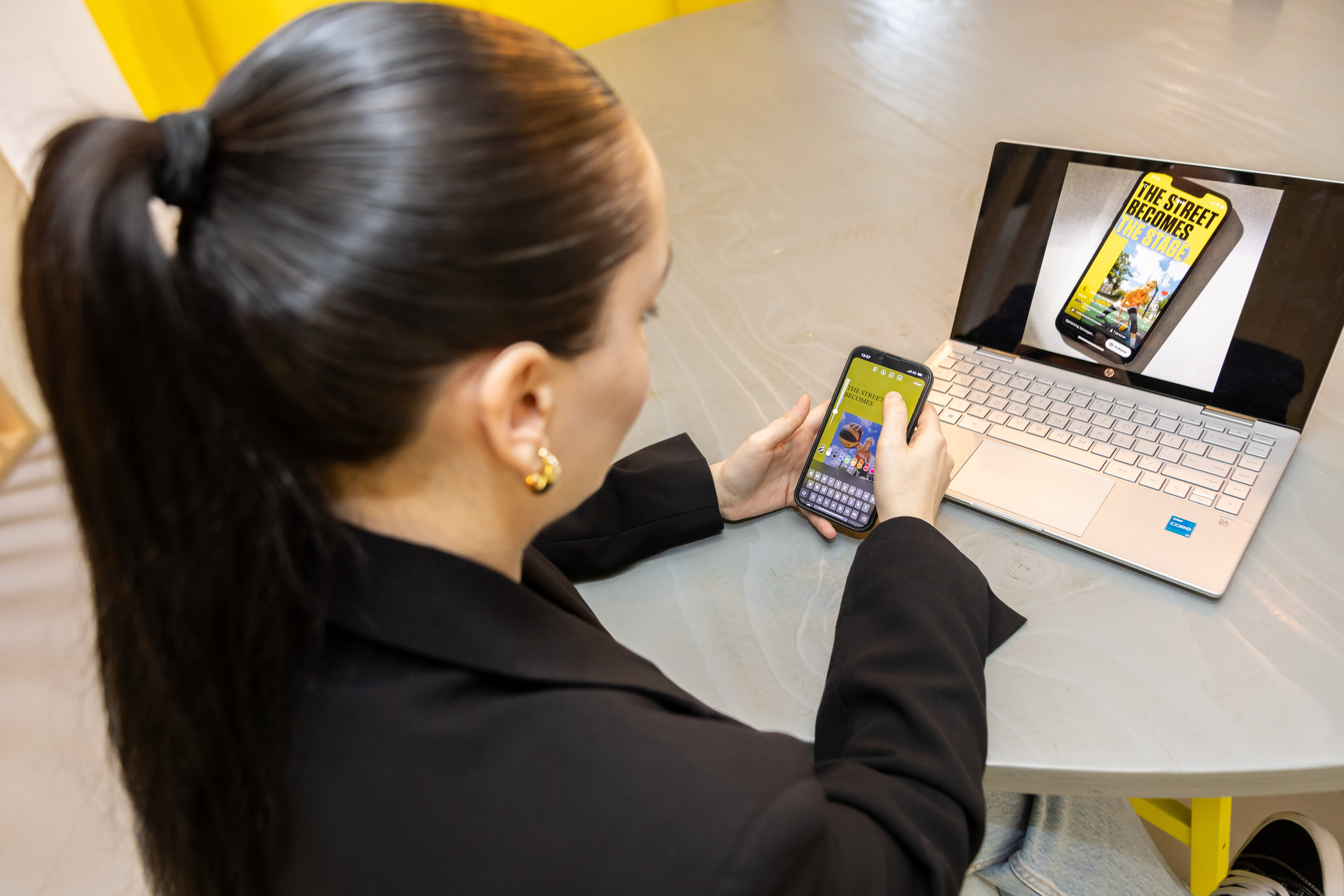 Mediamaker werkt aan digitale media en bekijkt content op smartphone en laptop met ontwerpprogramma's.