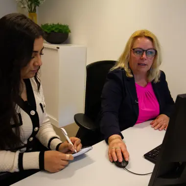 Begeleider legt administratieve taken uit aan student tijdens overleg in kantooromgeving