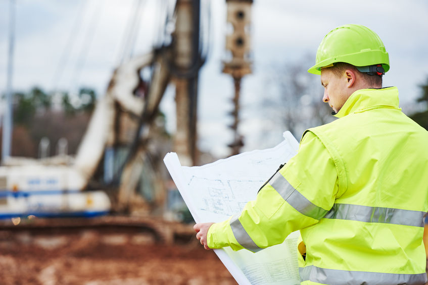 Werkvoorbereider bekijkt bouwtekening bij een bouwplaats voor gespecialiseerde aanneming
