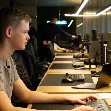 Student werkt geconcentreerd op computer met softwareontwikkeling in een moderne lesomgeving