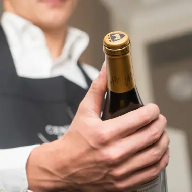 Gastheer presenteert een fles wijn, voorbereid om gasten een fijne horecabeleving te bieden