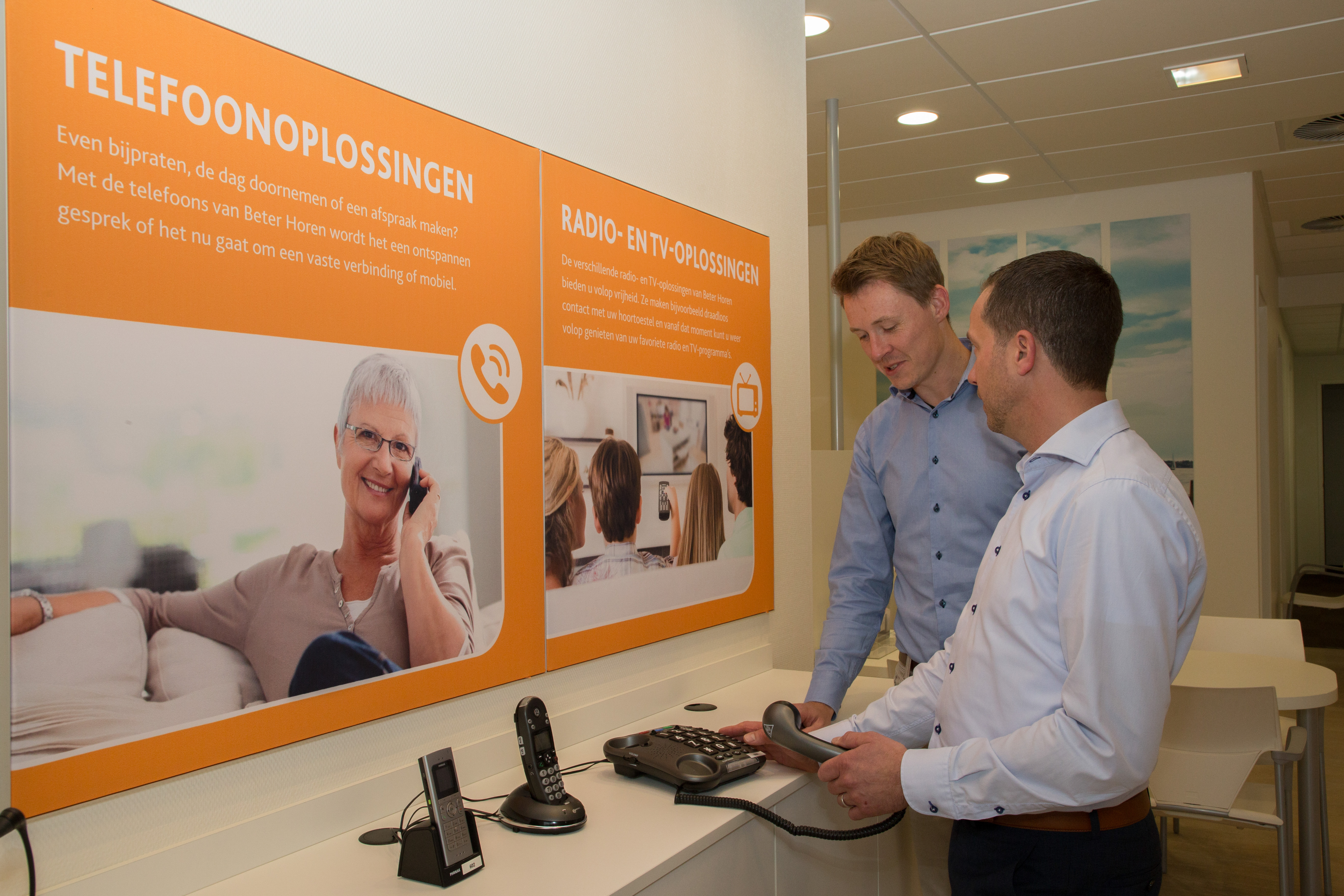 Audicien legt klant uit hoe verschillende gehoorhulpmiddelen werken in een winkelomgeving.