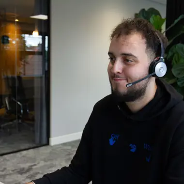 Medewerker klantenservice met headset ondersteunt zakelijke vragen over handel en logistiek