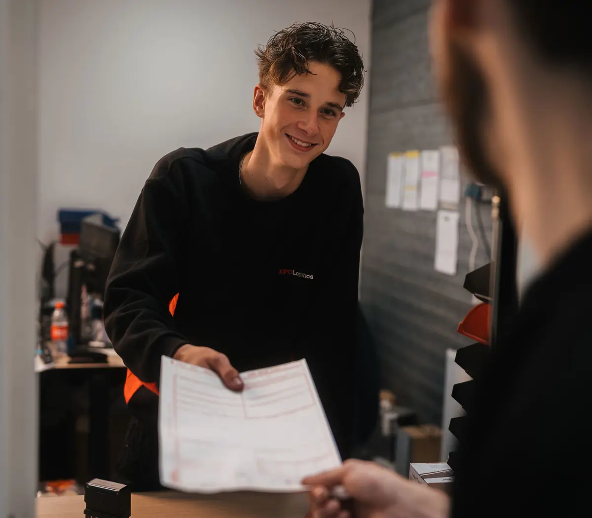 Medewerker overhandigt een document aan een collega in een zakelijke werkomgeving