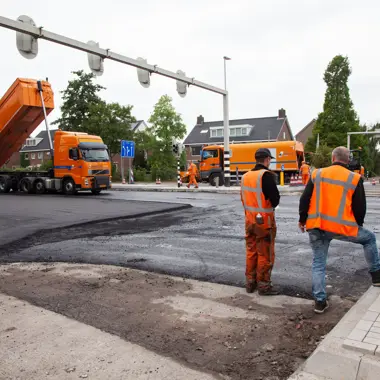 Vakspecialisten aan het werk bij de aanleg van een weg met machines en asfalt in een woonwijk