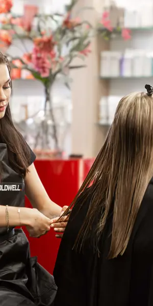 Student oefent knippen in een kappersopleiding, gericht op haarverzorging en klantadvies.