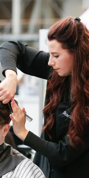 Leerling die haar knipt en stylet tijdens praktijkles binnen de opleiding uiterlijke verzorging.