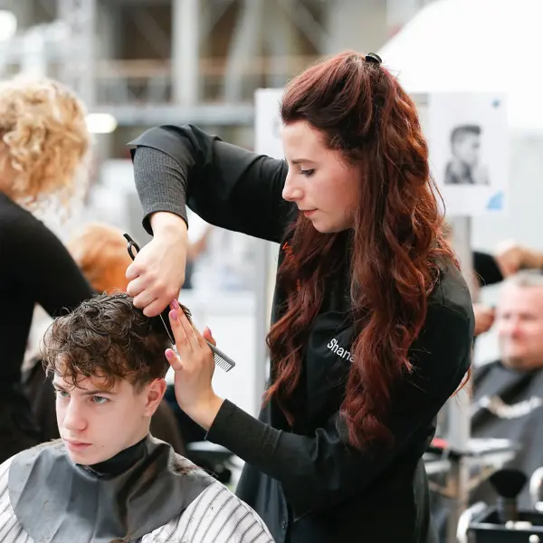 Leerling die haar knipt en stylet tijdens praktijkles binnen de opleiding uiterlijke verzorging.