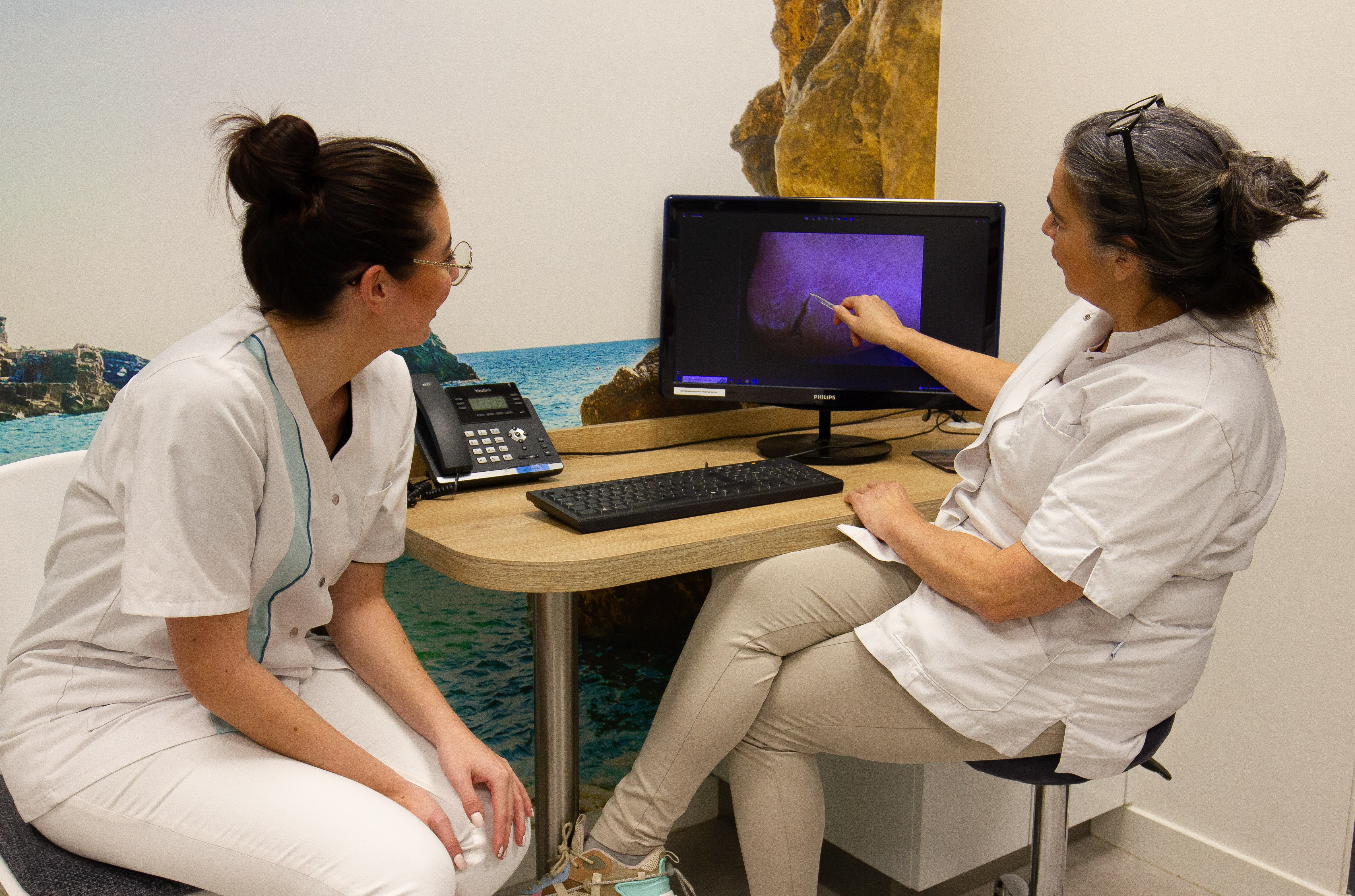 Medisch pedicures bekijken een voetonderzoek op een computerscherm in een behandelkamer